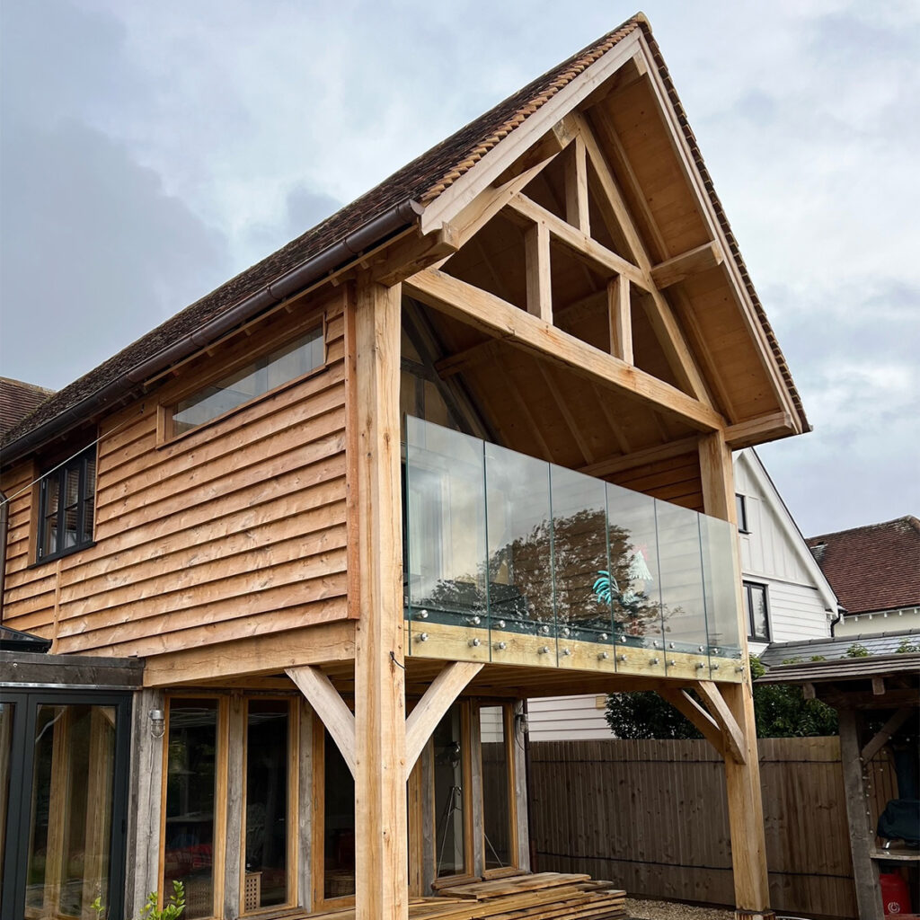 Clear toughened laminated glass balustrade acting as a barrier on the open edge of an enclosed, first floor decking area.